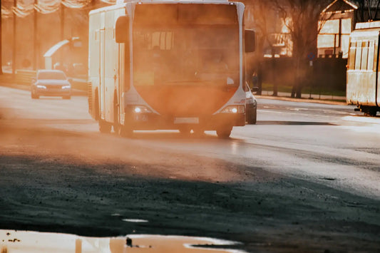 Un bus qui roule sur la route, avec de la fumée liée à la pollution de l'air