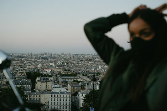 Ville avec air pollué en arrière plan et femme avec masque anti pollution en premier plan.
