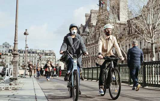 Deux personnes avec masques anti-pollution, faisant du vélo en ville.