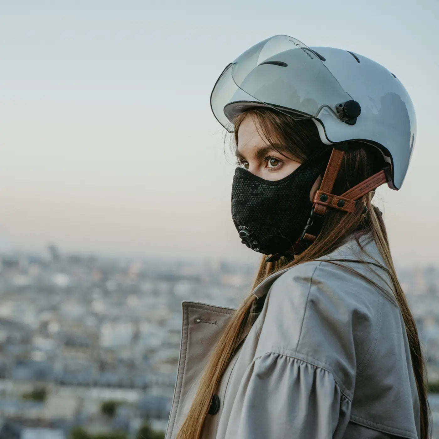 Femme avec un casque et un masque R-PUR devant Paris le matin