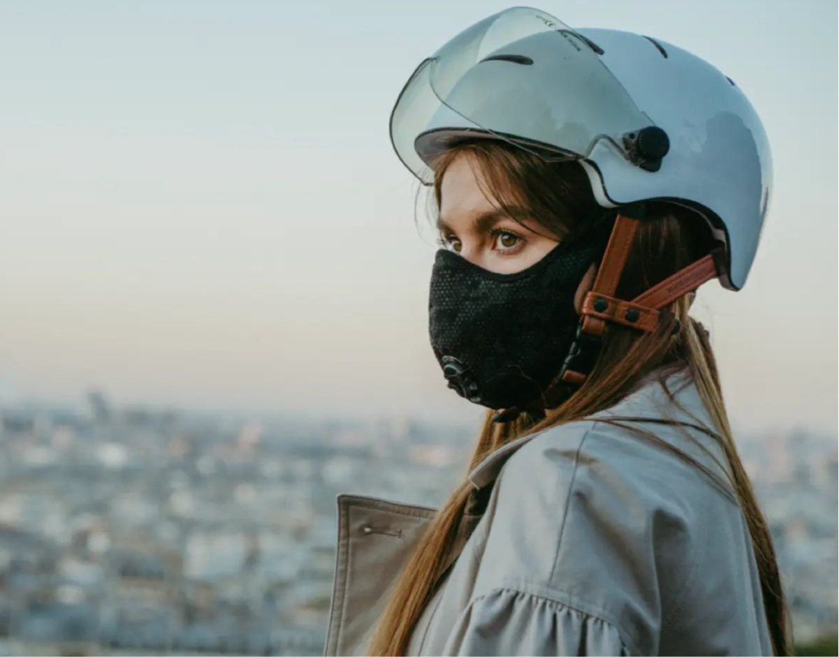 femme qui porte un masque antipollution avec un casque de vélo en ville