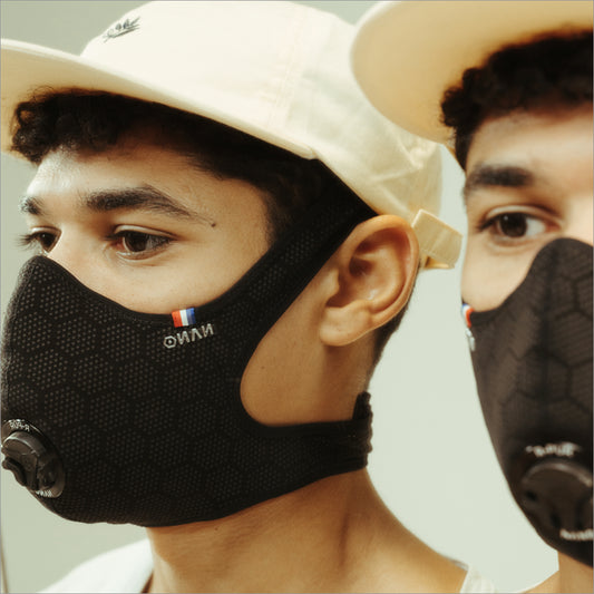 Close view of two young men in beige caps wearing black R-PUR masks, suitable as a travel mask for city commutes