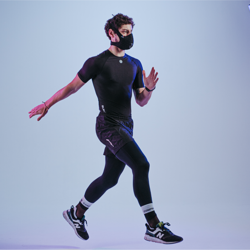 Runner mid-stride in studio wearing a black pollution mask for running.
