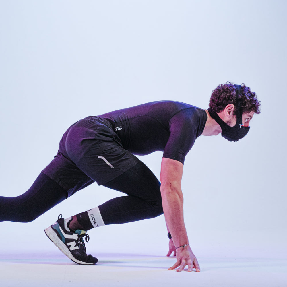 Sprinter in start position wearing a black R-PUR running pollution mask and compression gear.
