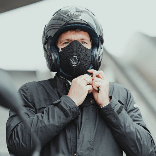 Rider in a motorcycle helmet tightening the strap, wearing a black motorcycle R-PUR mask