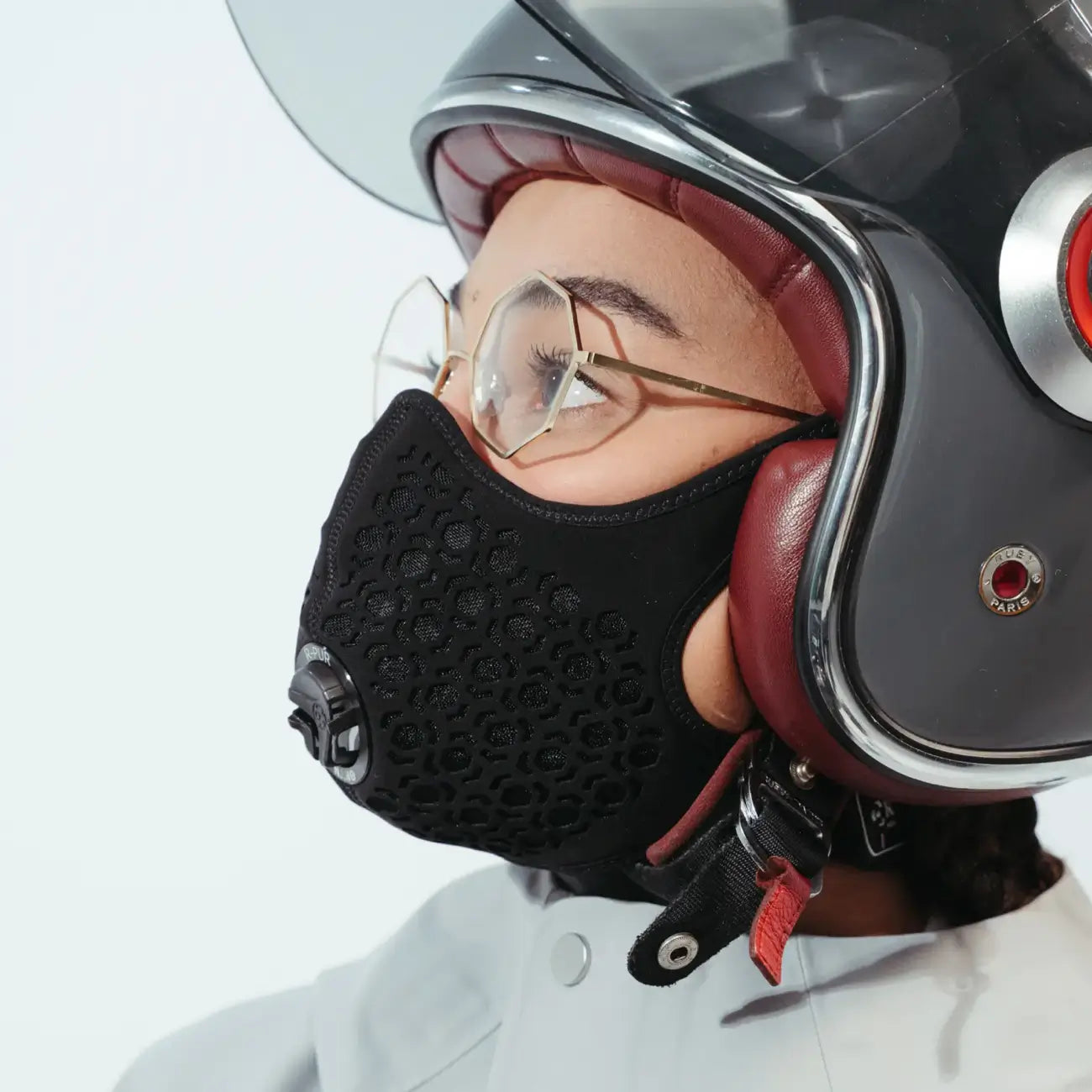 Person in an open-face helmet and glasses wearing a black R-PUR motorcycle mask, side profile